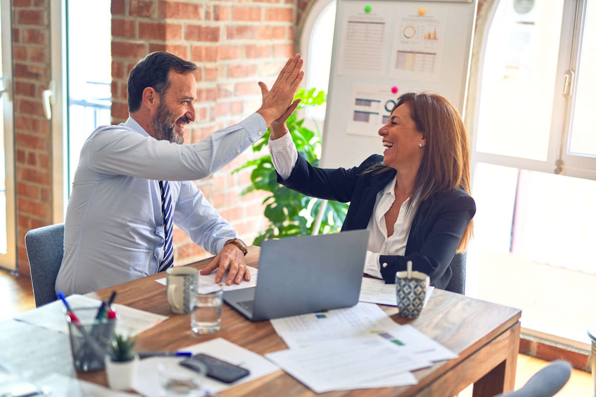 A couple celebrating while planning finances together at a desk